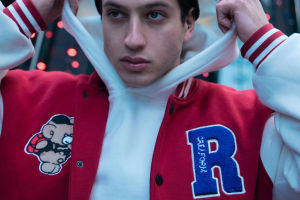 Male model in hoodie wearing varsity jacket with custom patches