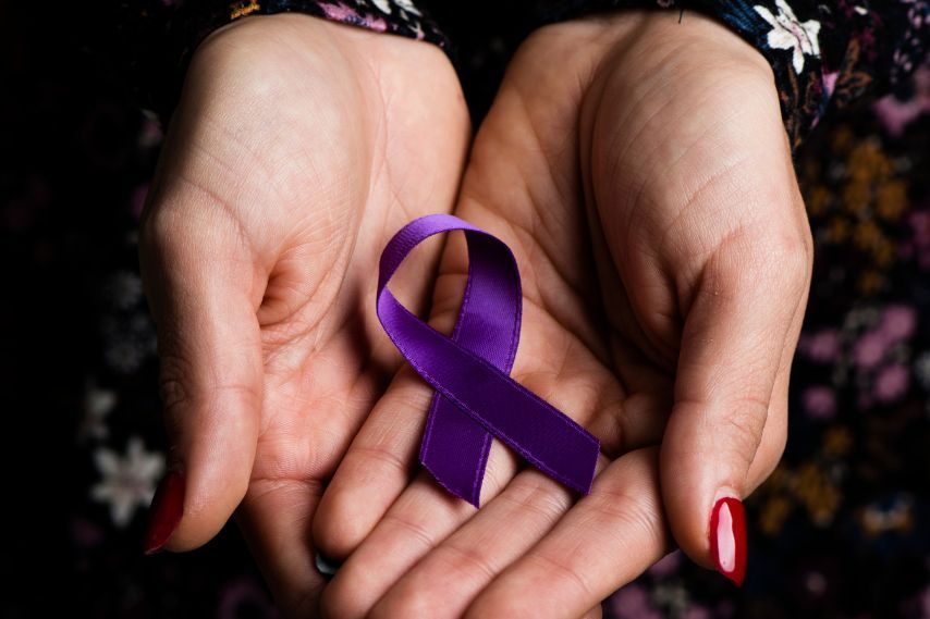 womans hand holding purple ribbon
