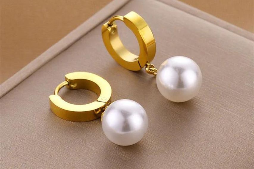 gold hoops pearl earrings on surface