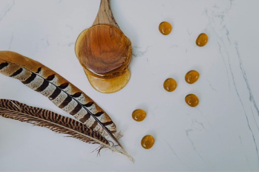 honey spoon drops and feathers on marble counter