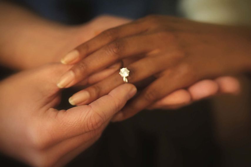 hands putting on diamond engagement ring
