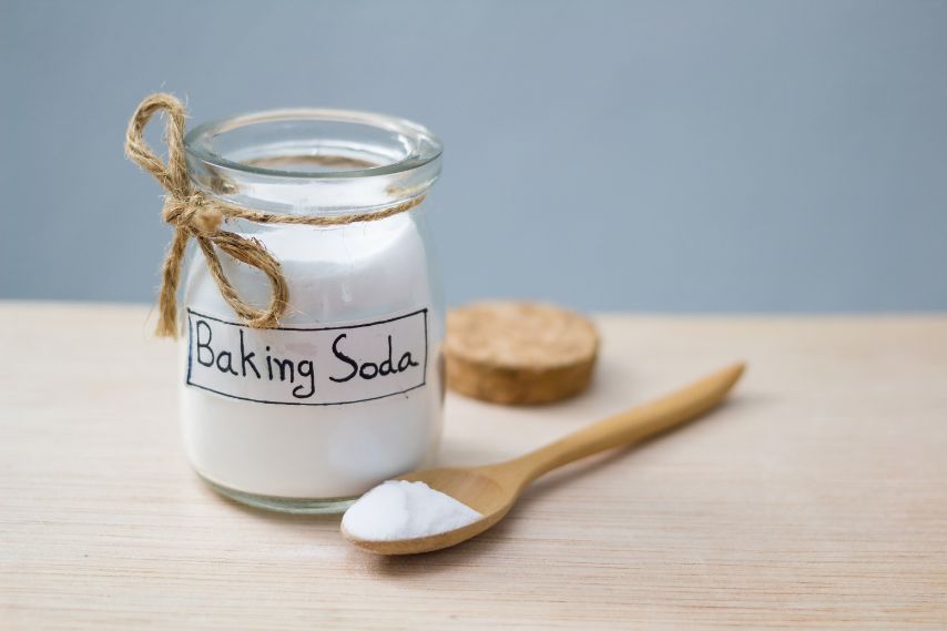 jar of baking soda and wooden spoon on table