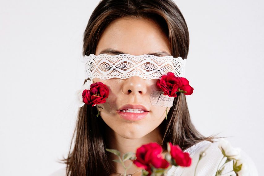  woman in white shirt with white lace blindfold and red flowers