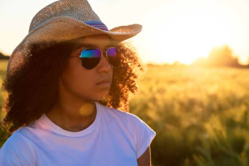 Woman wearing aviator sunglasses with straw hat